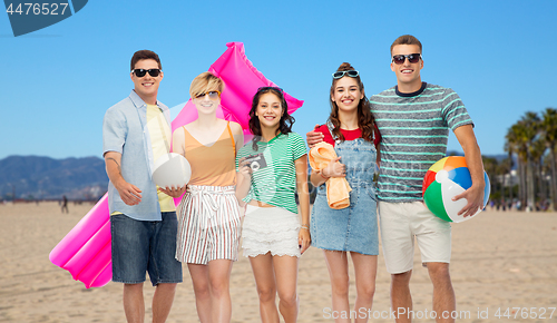 Image of happy friends with beach and summer accessories