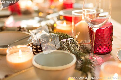 Image of pine cone and candles burning on christmas table