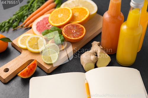 Image of close up of fruits, juices and notebook on table