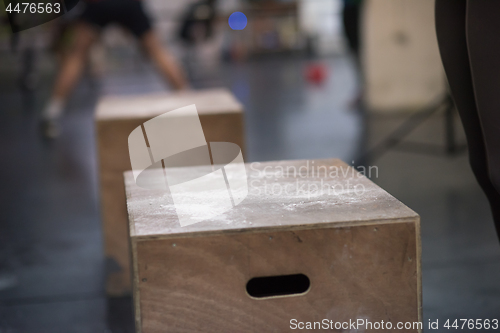 Image of black woman is performing box jumps at gym