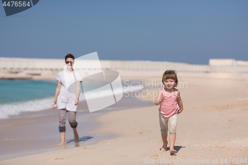 Image of mother and daughter running on the beach