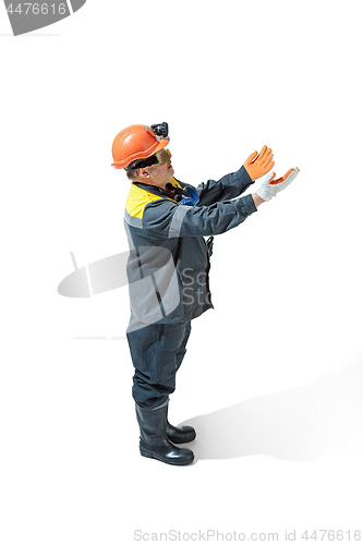 Image of The studio shot of senior bearded male miner standing at the camera on a white background.