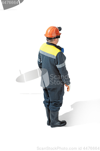 Image of The studio shot of senior bearded male miner standing at the camera on a white background.