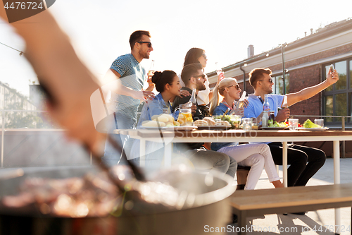 Image of happy friends taking selfie at rooftop party