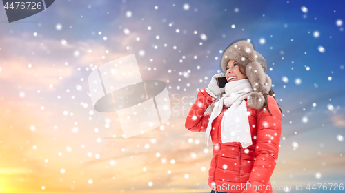 Image of woman calling on smartphone in winter over snow