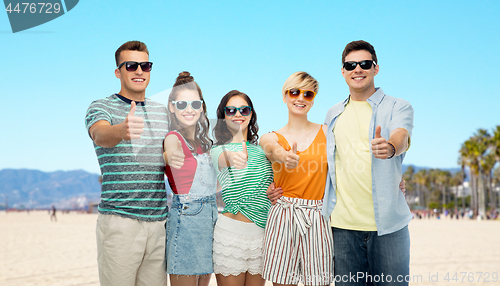 Image of happy friends showing thumbs up over venice beach