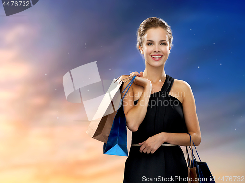 Image of happy woman in black dress with shopping bags