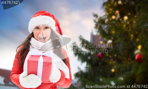 Image of happy woman with gift over christmas tree
