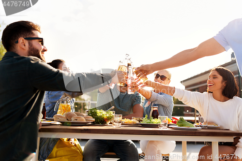 Image of happy friends toasting drinks at rooftop party