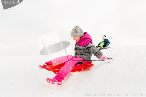 Image of happy little girl sliding down on sled in winter