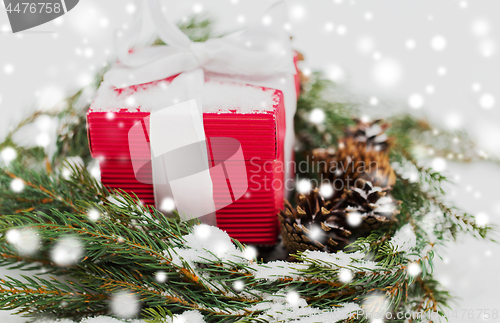 Image of christmas gift and fir wreath with cones on snow