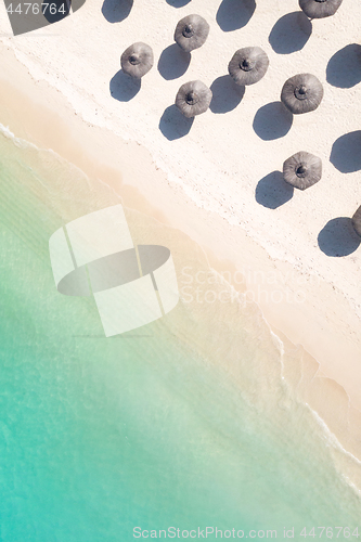 Image of Aerial view of amazing tropical white sandy beach with palm leaves umbrellas and turquoise sea.