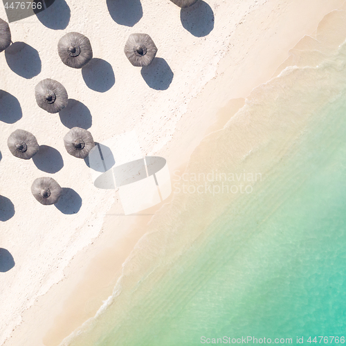 Image of Aerial view of amazing tropical white sandy beach with palm leaves umbrellas and turquoise sea.