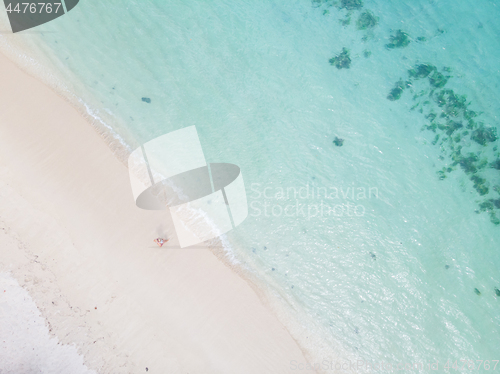 Image of Aerial shot of woman enjoying the picture perfect white tropica beach on Mauritius island.