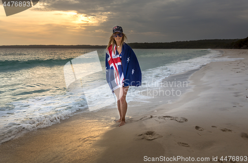 Image of Woman draped in Australian Flag on a beach in early morning