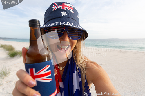 Image of Australian culture - lazy day on beach girl with a beer