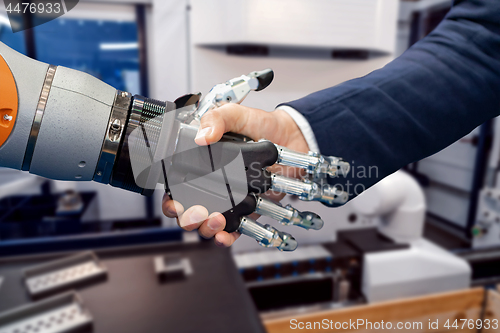 Image of Hand of a businessman shaking hands with a Android robot.