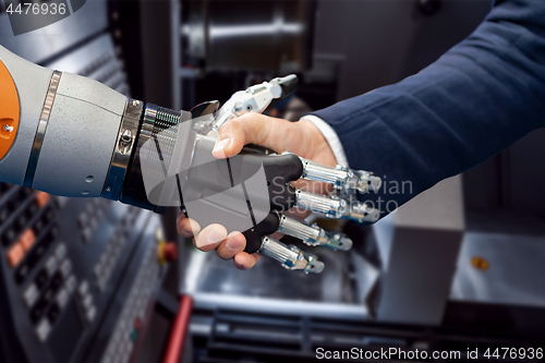 Image of Hand of a businessman shaking hands with a Android robot.