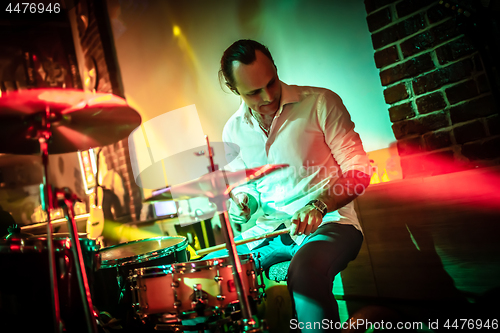 Image of Drummer playing on drum set on stage.