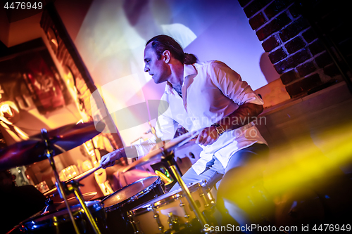 Image of Drummer playing on drum set on stage.