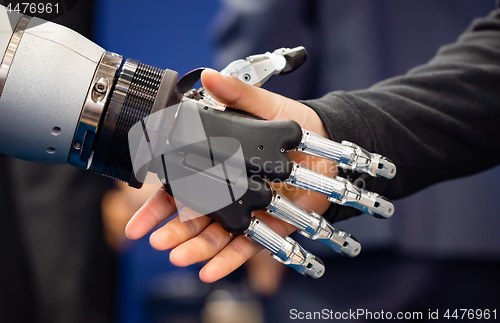 Image of Hand of a businessman shaking hands with a Android robot.