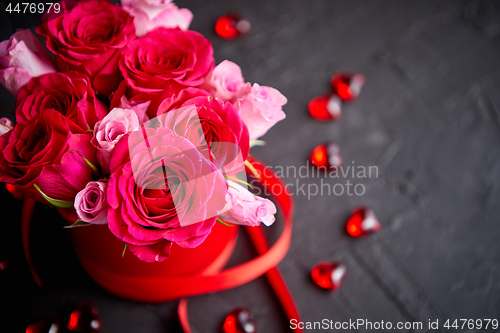 Image of Pink roses bouquet packed in red box and placed on black stone background