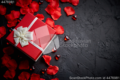 Image of Gift box on black stone table. Romantic holiday background with rose petals