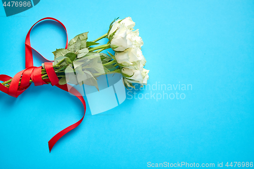 Image of Bouquet of white roses with red bow on blue background