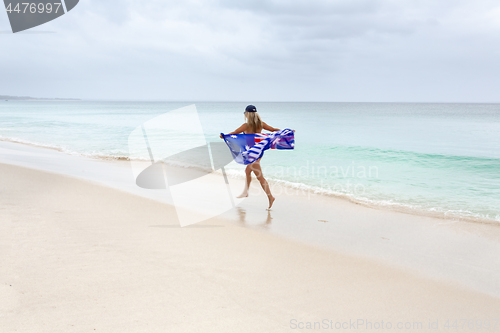 Image of Female in motion with Australian flag running along the beach