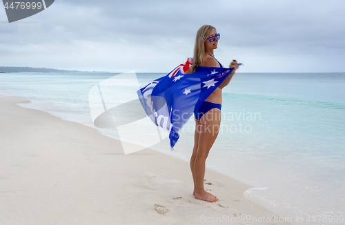 Image of Female standing on the beach with Aussie flag in the breeze