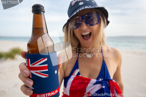 Image of Australian woman holding offering a bottle of beer