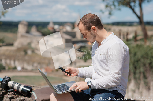 Image of Handsome businessman with laptop talking on the phone