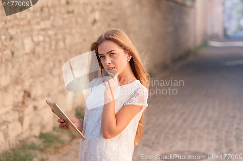 Image of beautiful young woman in white dress using tablet