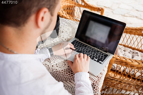 Image of man working with laptop computer and sitting on sofa