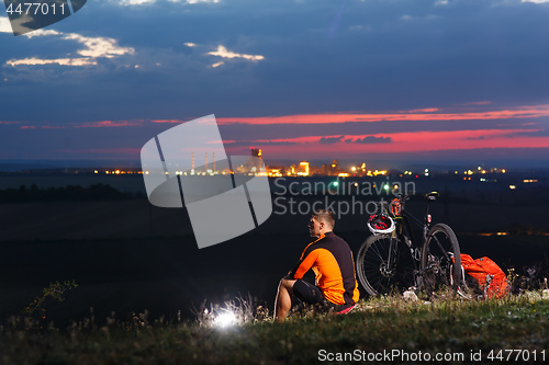 Image of guy has a rest sitting near his bike