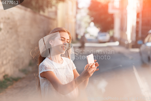 Image of Girl take selfie from hands with phone on summer city