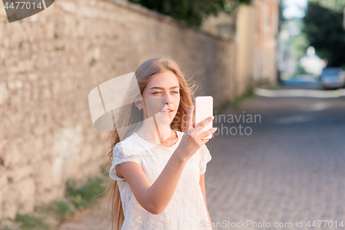 Image of Girl take selfie from hands with phone on summer city