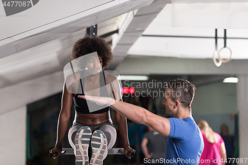 Image of black woman doing parallel bars Exercise with trainer