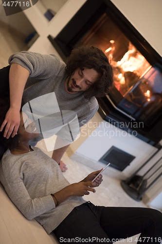 Image of multiethnic couple using tablet computer on the floor