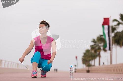 Image of Young woman tying shoelaces on sneakers