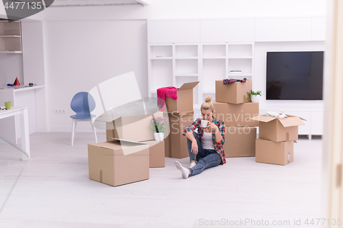 Image of woman with many cardboard boxes sitting on floor