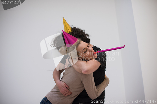 Image of couple in party hats blowing in whistle