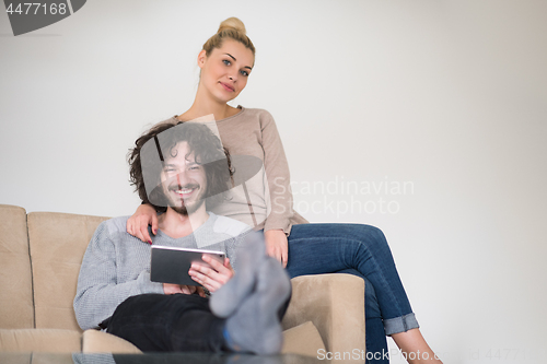 Image of couple relaxing at  home with tablet computers