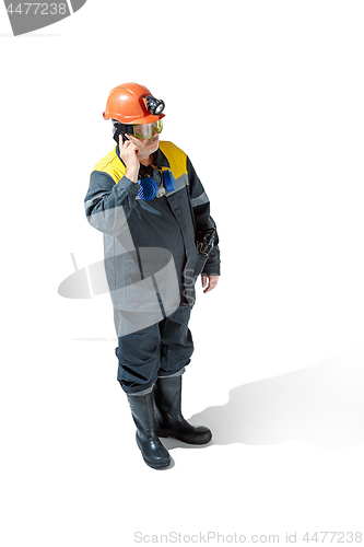 Image of The studio shot of senior bearded male miner standing at the camera on a white background.