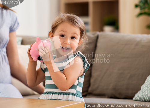 Image of happy little girl with piggy bank