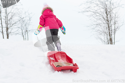 Image of little girl with sleds on snow hill in winter