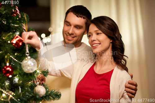 Image of happy couple decorating christmas tree at home