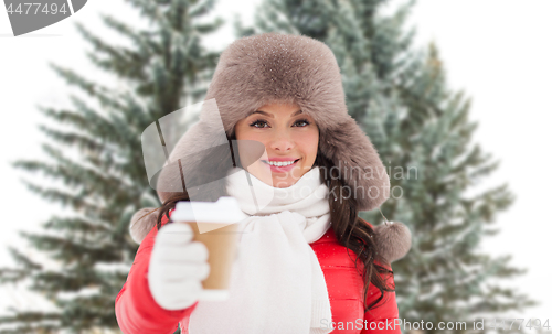Image of woman in fur winter hat with coffee over fir trees