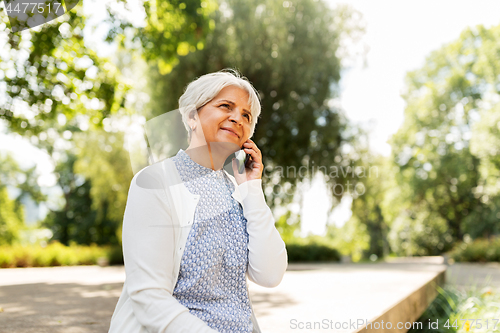 Image of happy senior woman calling on smartphone in summer