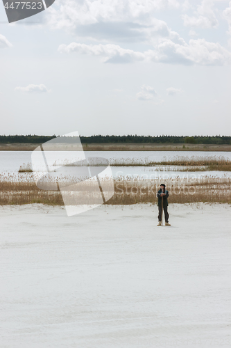 Image of Man Standing By The Lake Among White Quartz Sand 